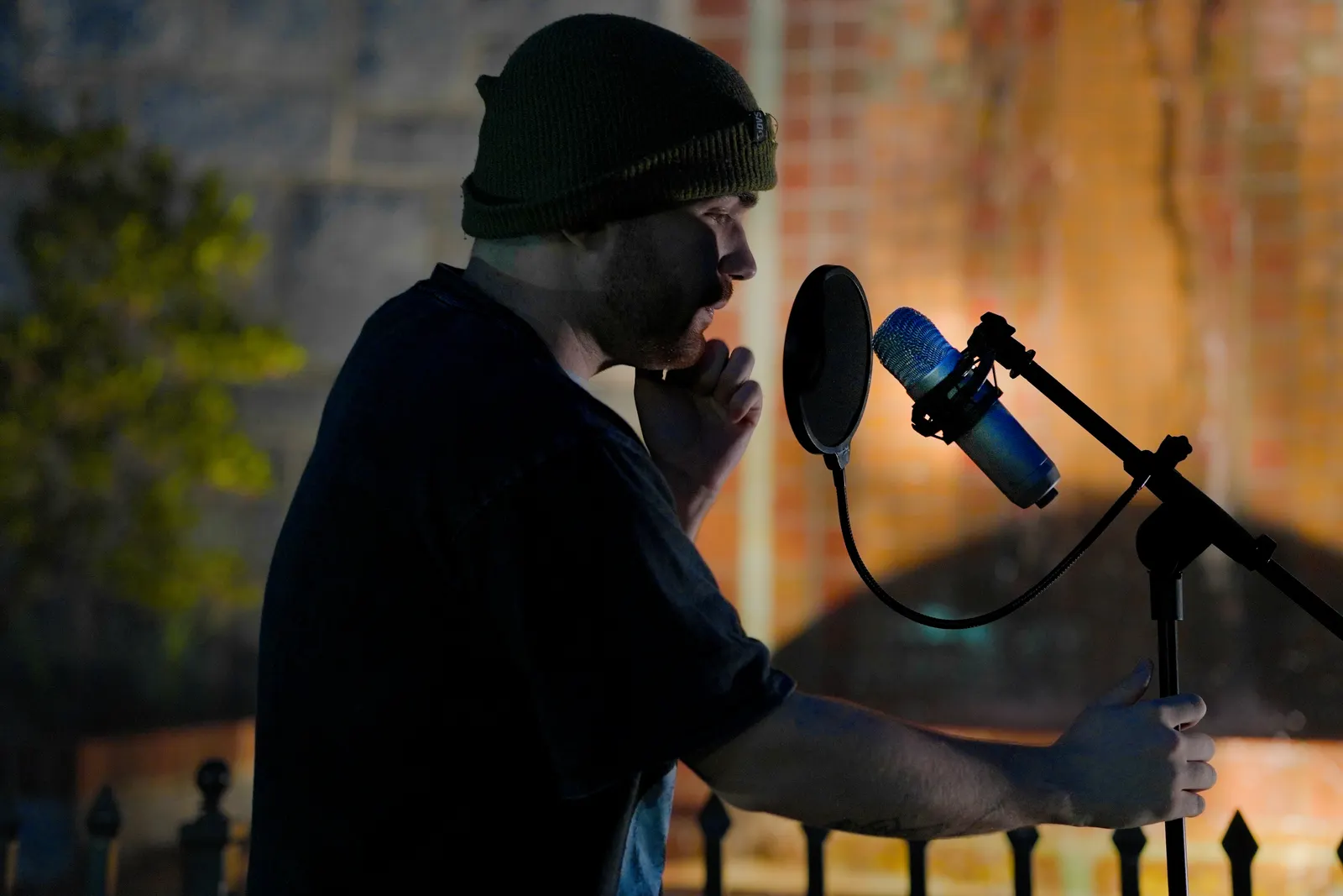 A vocalist holding the mic stand mid-phrase, lit by warm light