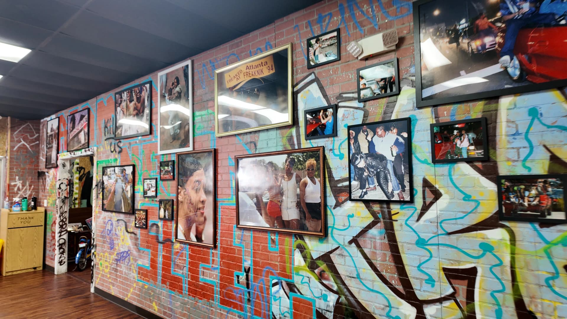 TheBando gallery wall of Black history photographs and graffiti art on exposed brick inside the Atlanta Westside restaurant